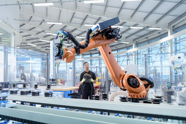 Artificial intelligence and the law: An industrial robot being programmed by a human being.