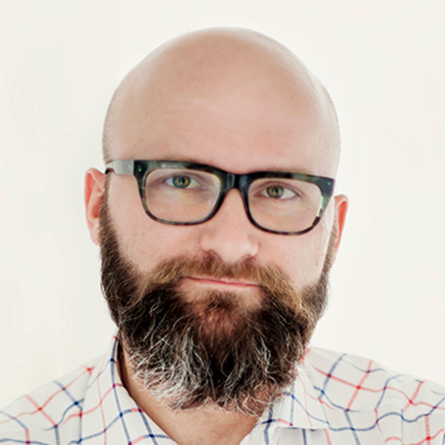 Dr. hab. Tomasz Piekot, u kariranoj košulji, naslonjen je na zid s prekriženim rukama.