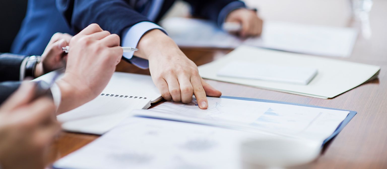 Outsourcing debt collection: Man in a suit points his finger at a document.