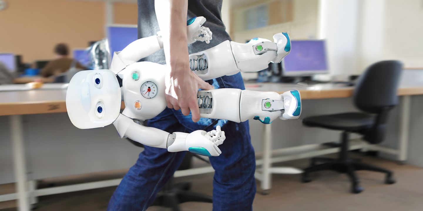 AI in customer service: Staff member carries a robot through the office
