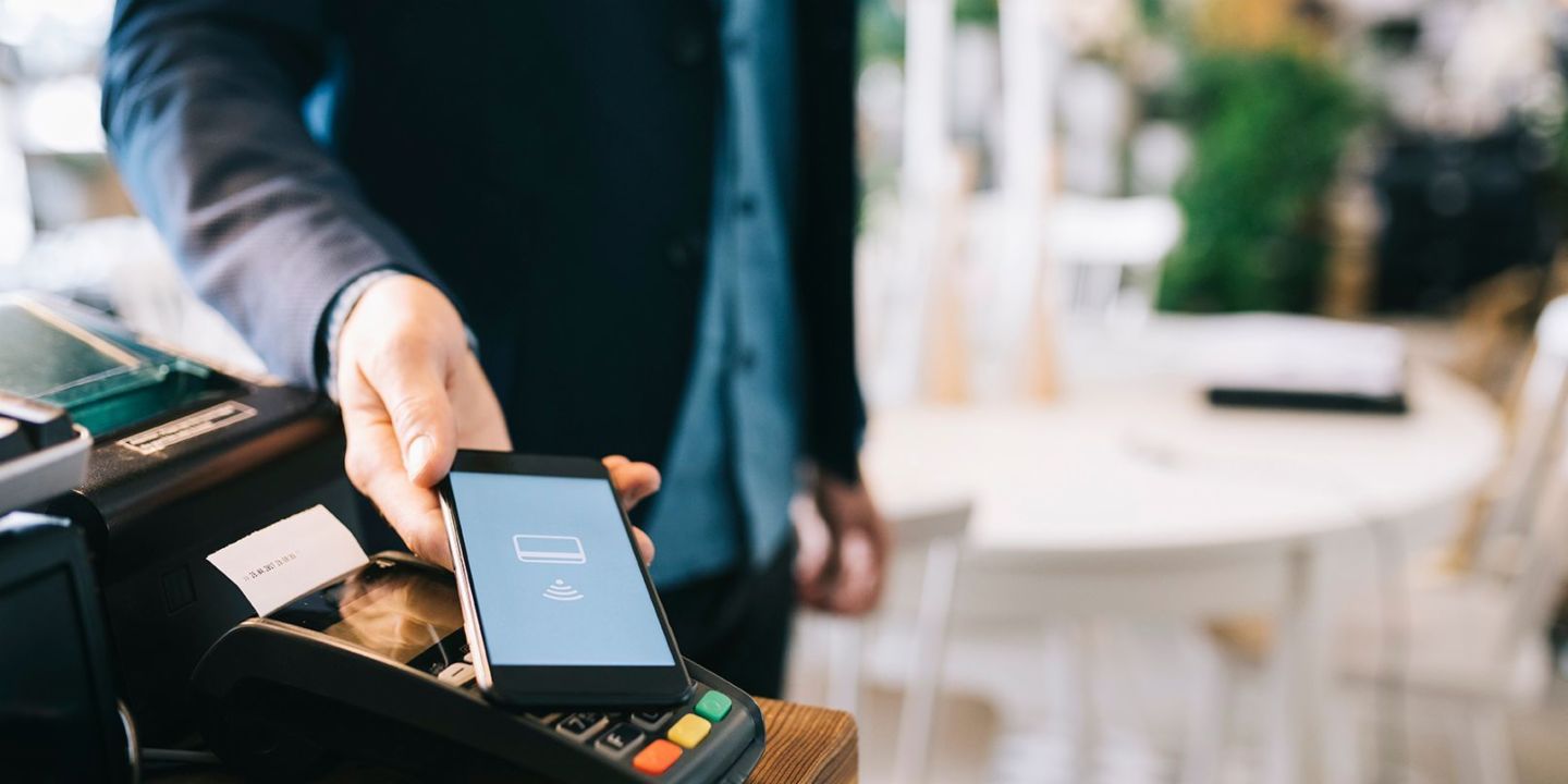 Digital betaling: Mand lægger sin mobiltelefon på en betalingsterminal 