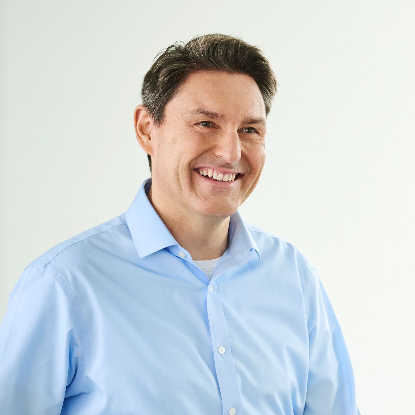 Stephan Ohlmeyer, az EOS Csoport Közép-Európáért felelős ügyvezető igazgatója Stephan Ohlmeyer, egy világoskék pólós férfi, mosolyogva áll egy világos szobában