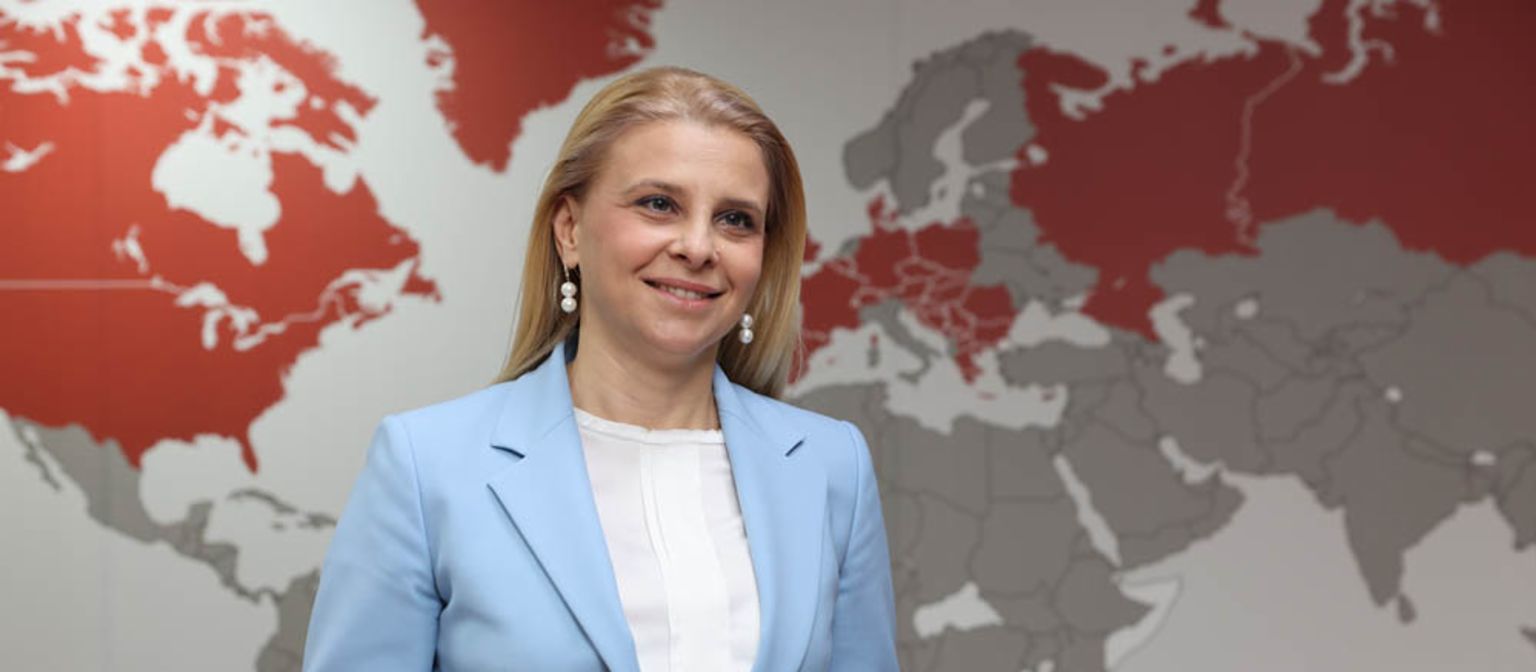 Katerina Bosevska Managing Director of EOS North Macedonia is standing in front of a world map