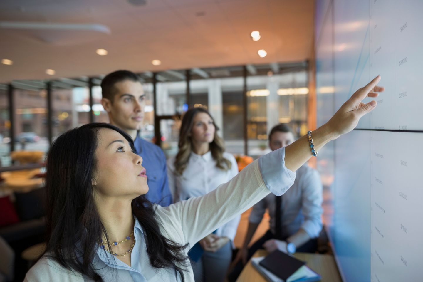 Value of data: A group of people stands in front of some monitors and evaluates data.
