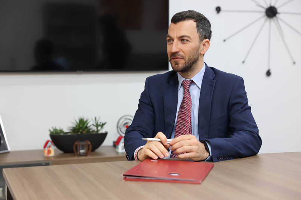 Vladislav Hadjidinev CEO of UNIBANKA is sitting at an office desk with a red folder in front of him